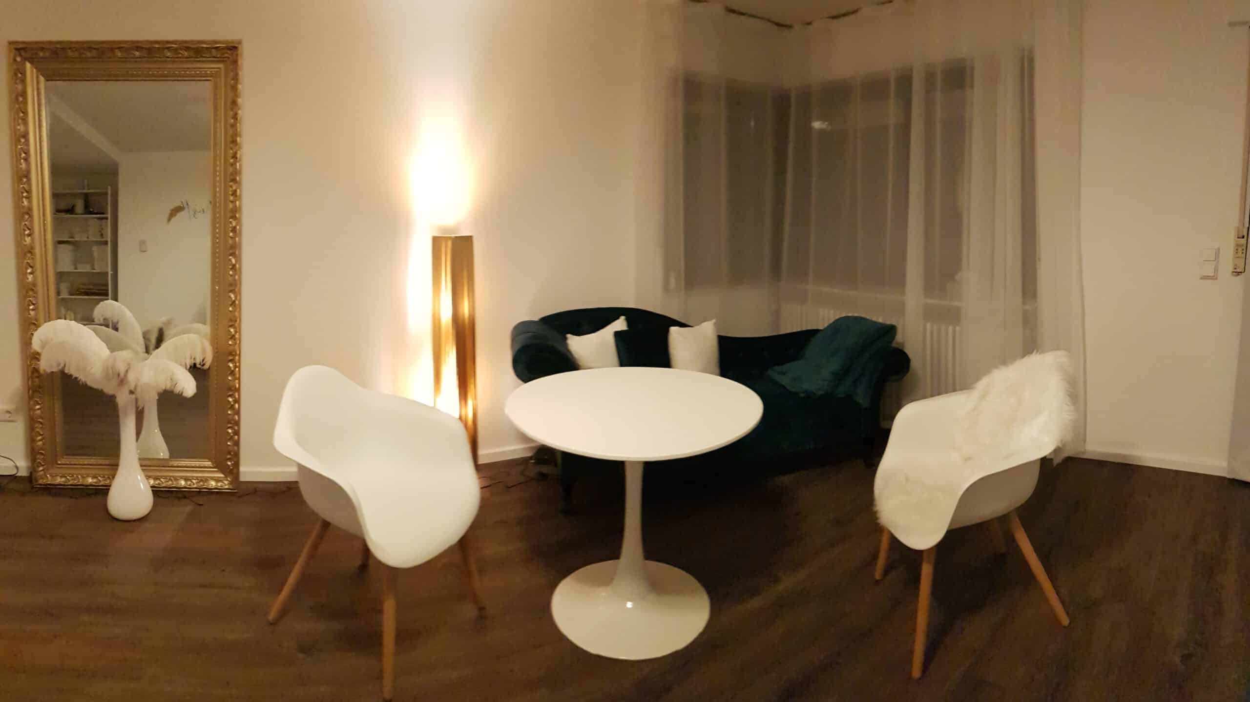 Wohnzimmer mit Sitzbereich, Sessel, Tisch und Dekoration, gemütliche Atmosphäre.